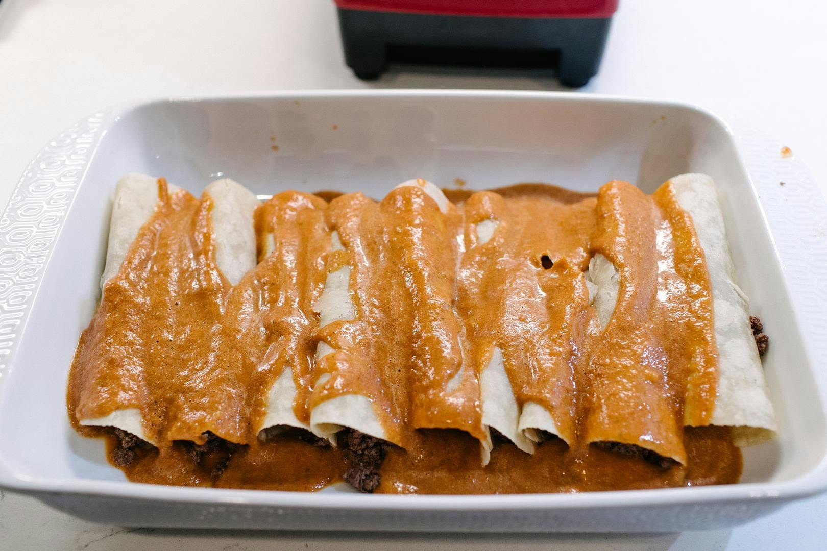 enchiladas with red sauce on top in baking dish