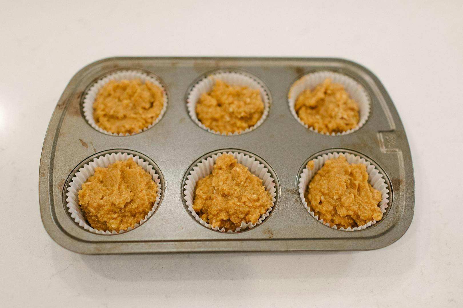 raw muffin batter in lined muffin tin