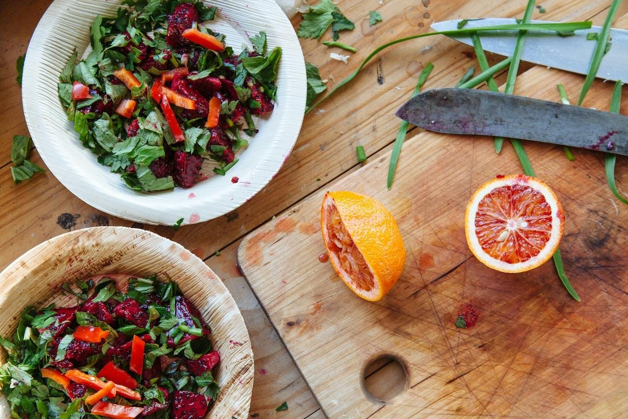 two salads and two blood orange halves on a cutting board