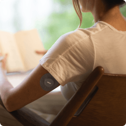 Woman sits in chair with Veri CGM on her arm