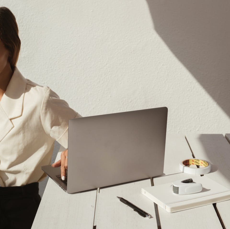 A woman sits behind her laptop, preparing for an online coaching session with a client.