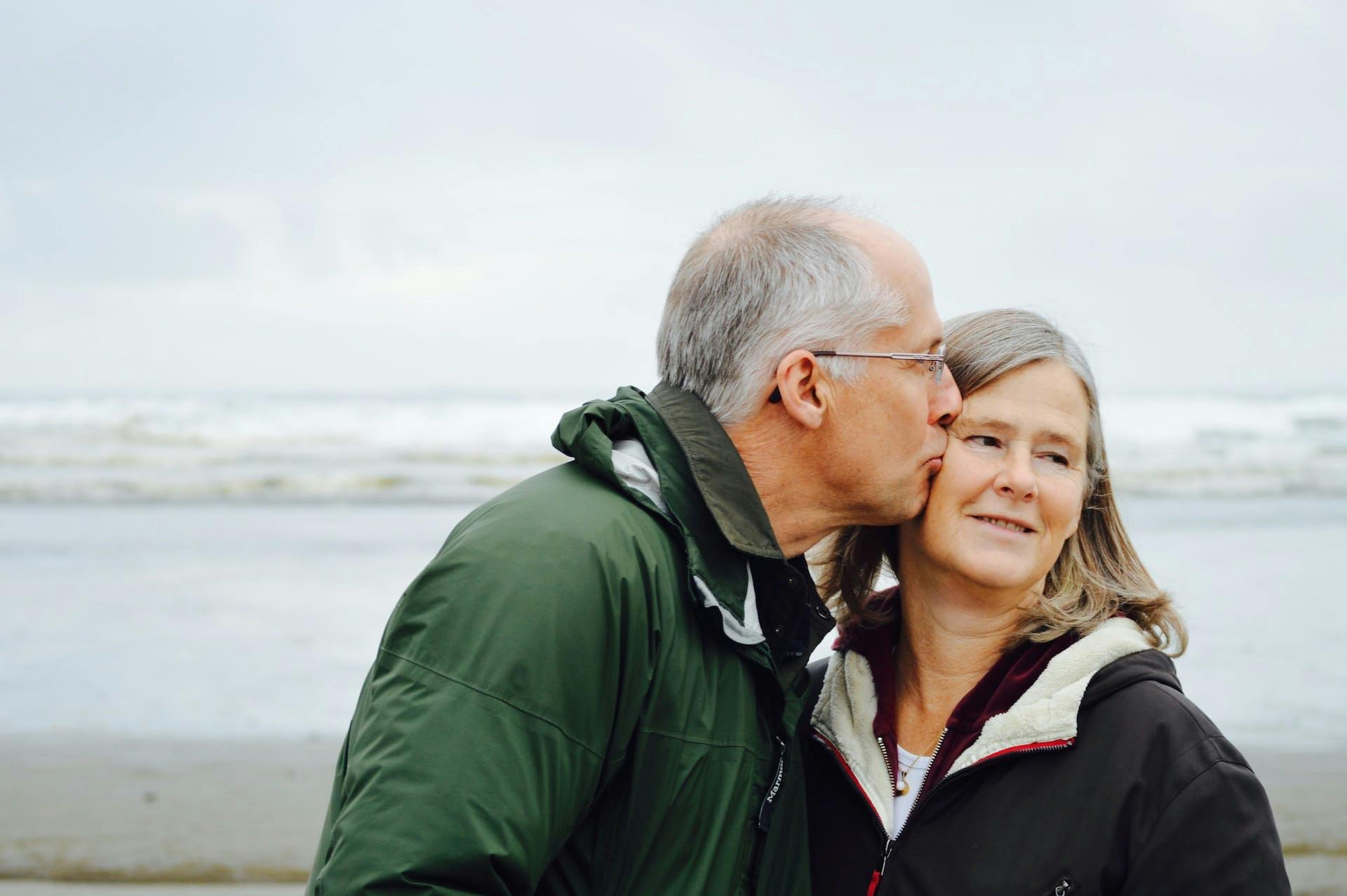 older man kissing a woman on the cheek at the beach
