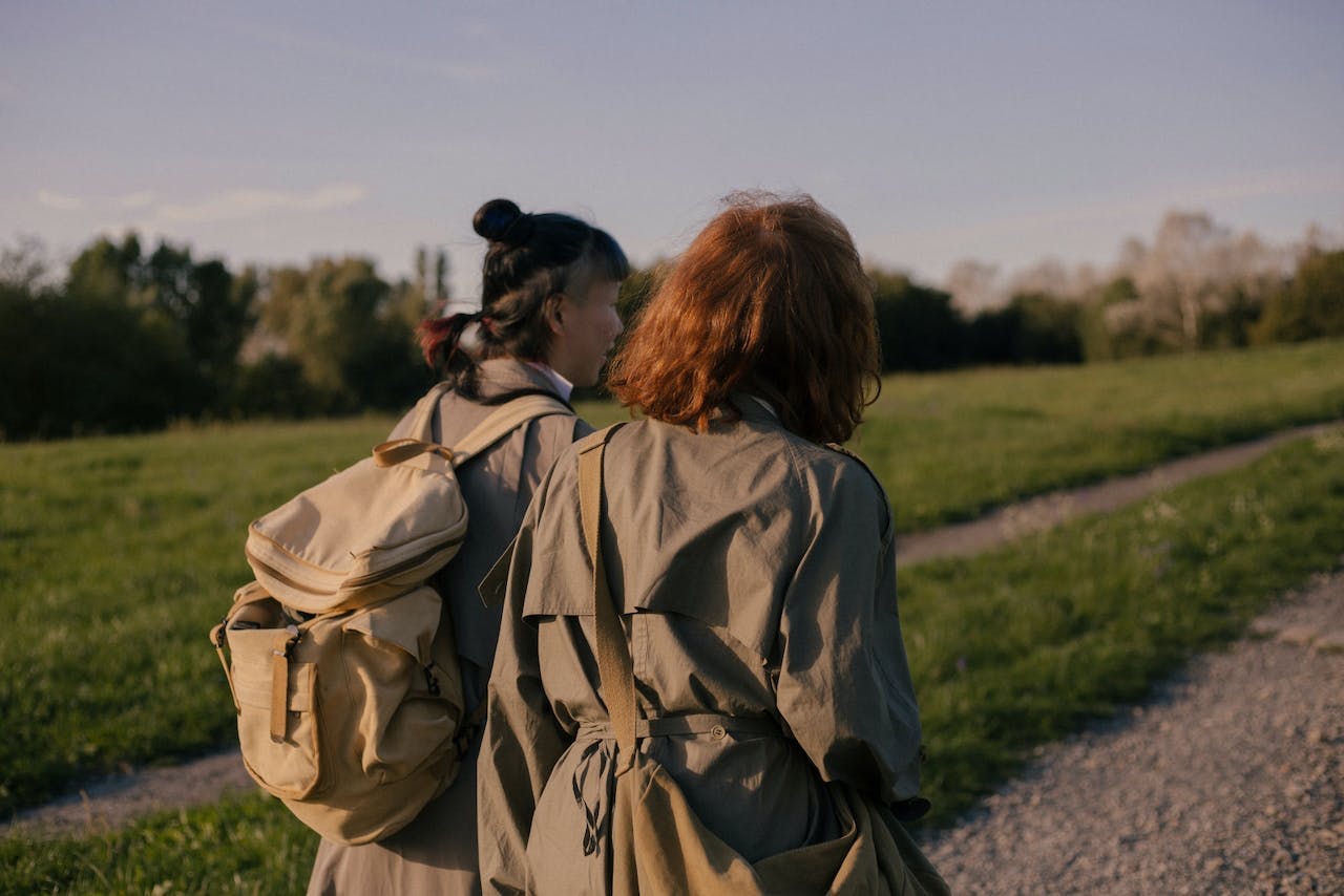two women hiking on a gravel trail surrounded by a grassy area