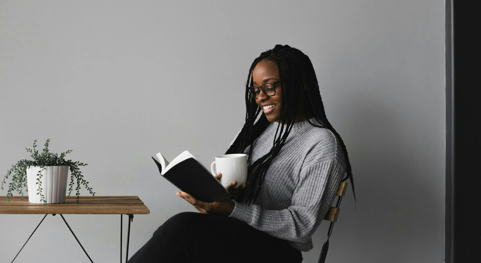 woman reading book and holding mug