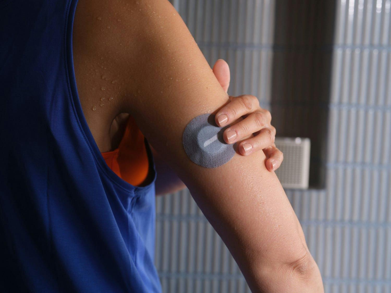 woman applying a patch to her continuous glucose monitor